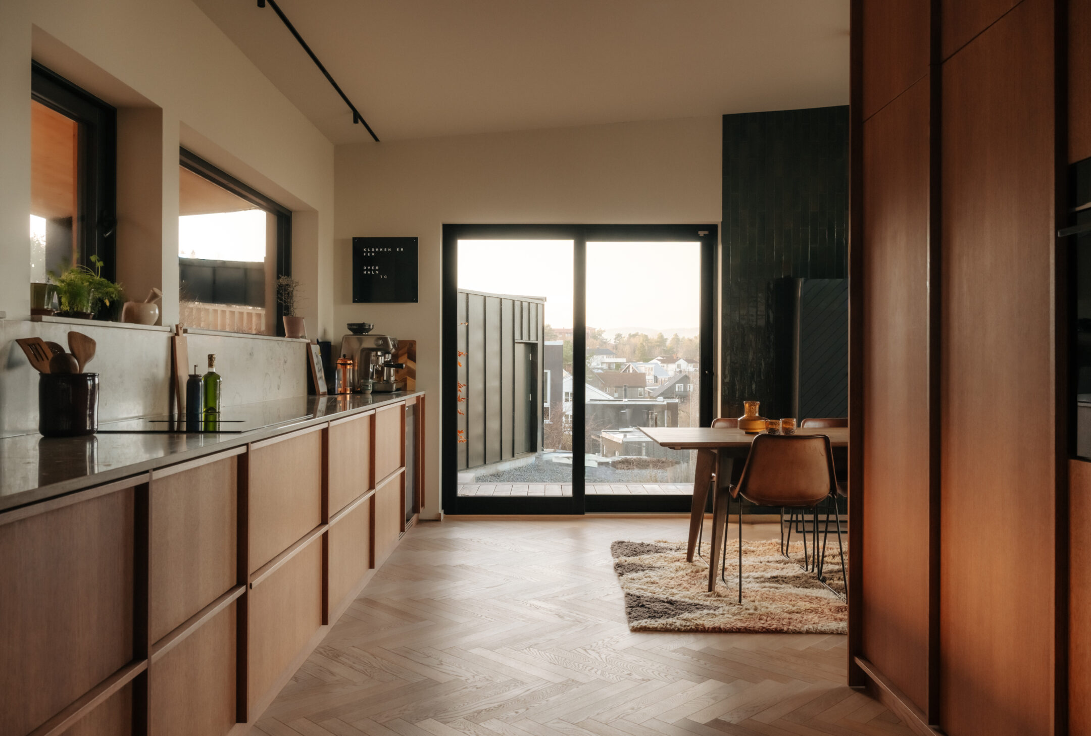 Modern kitchen with wooden cabinets, marble counter, and glass doors opening to a patio area.